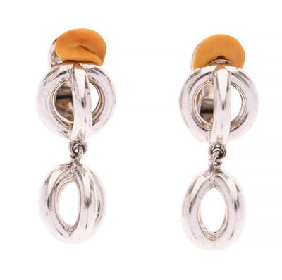 une paire de boucles d'oreilles argentées et orange sur fond blanc