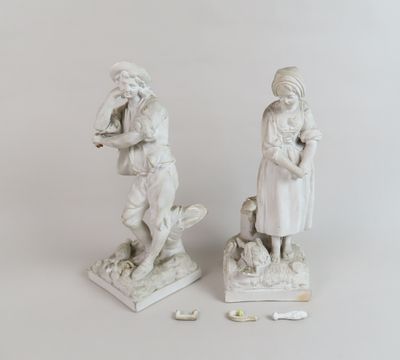 une paire de statues blanches représentant une femme et un enfant accompagnés d'un chien