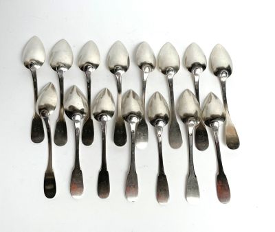 six spoons and a spoon rest in a row on a white surface