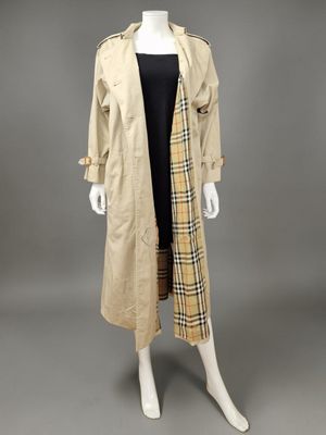 a mannequin wearing a beige trench coat and black dress
