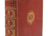 un vieux livre avec une couverture rouge et des bordures dorées sur fond blanc