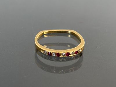a gold ring with red and white stones on a black surface