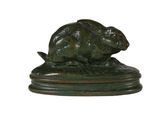une sculpture en bronze représentant un lapin sur un socle