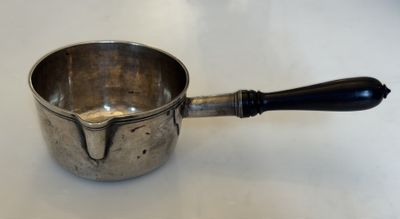 une tasse en argent avec une anse noire posée sur une table blanche