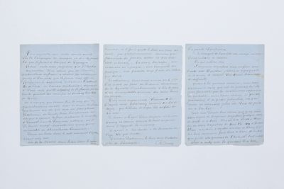 trois feuilles de papier couvertes d'écriture, posées sur une table
