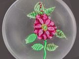 une assiette en verre ornée d'une fleur, posée sur une table