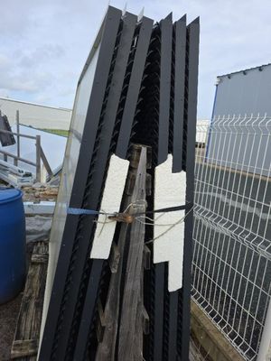 plusieurs morceaux de bois sont empilés les uns sur les autres devant une clôture