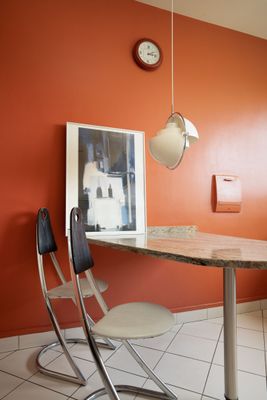 une table et des chaises dans une pièce où est accrochée une horloge au mur