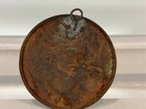 an old coin with a face on it sitting on top of a table