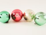 several shiny christmas ornaments are arranged in a row on a white surface