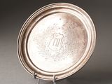 a silver plate with a monogram on it sitting on a stand