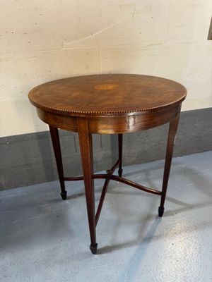 une petite table ronde avec un plateau en bois posée sur un sol bleu