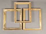 three gold picture frames on a gray wall with a white background