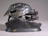 a statue of a bird on a rock with a bird in it ' s beak