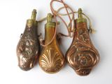 three antique brass bottle ornaments on a white surface