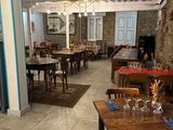 many tables and chairs in this restaurant with a stone wall