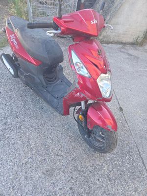 a red scooter parked on the side of the road