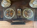 trois plateaux en verre posés sur une table en bois sur laquelle se trouve une horloge
