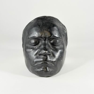 une sculpture noire représentant la tête d'un homme aux yeux fermés