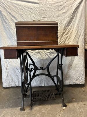 an old sewing machine sitting on a table in front of a white sheet