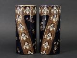 two vases with gold and blue designs on them sitting on a table