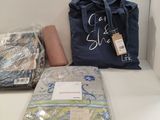 un sac bleu posé sur une étagère blanche, à côté d'une pile de couvertures