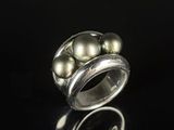 a close up of a silver ring with pearls on a black surface