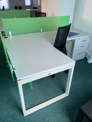 a white desk with green dividers and a black chair