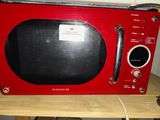 un micro-ondes rouge posé sur une table en bois