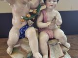 a figurine of two children sitting on top of a book