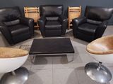 plusieurs chaises et une table basse dans une pièce dont l'un des murs est noir