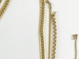 three gold necklaces and a bracelet on a white surface