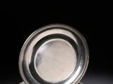 une assiette ancienne en argent posée sur une surface noire avec un fond noir