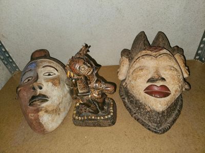 trois masques en bois posés les uns à côté des autres sur une table
