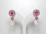 une paire de boucles d'oreilles en perles roses et blanches posées sur un présentoir blanc