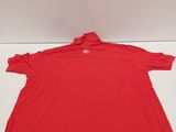 a red polo shirt sitting on top of a white table