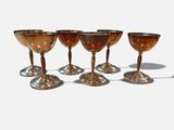 six wine glasses are lined up in a row on a white surface