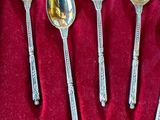 six silver spoons in a box with a red velvet lining