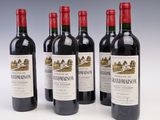 quatre bouteilles de vin rouge sont alignées sur une surface blanche