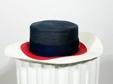 une poubelle blanche surmontée d'un chapeau rouge et bleu