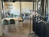 tables and chairs in a room with a large window and a coat rack