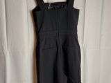 a black jumpsuit on a hanger against a white curtain
