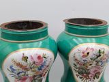 two vases with flowers painted on them sitting on a table