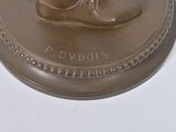 a bronze statue of a man ' s shoe on top of a plaque