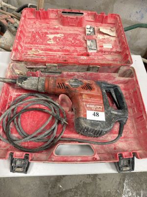 une boîte rouge contenant une perceuse et une cordelette