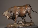 bronze statue of a bull on a rock on a gray background