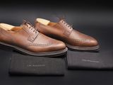 une paire de chaussures en cuir marron pour homme posée sur une surface noire