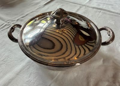 un plat en argent muni d'un couvercle, posé sur une table