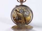 a silver pocket watch with gears on it on a white surface