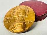 une médaille d'or posée sur une boîte rouge